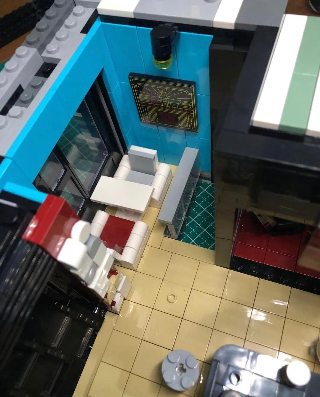 Overhead view of the upper floor of the modular restaurant set, showing tiled floors, blue accent walls, and white seating around a table.