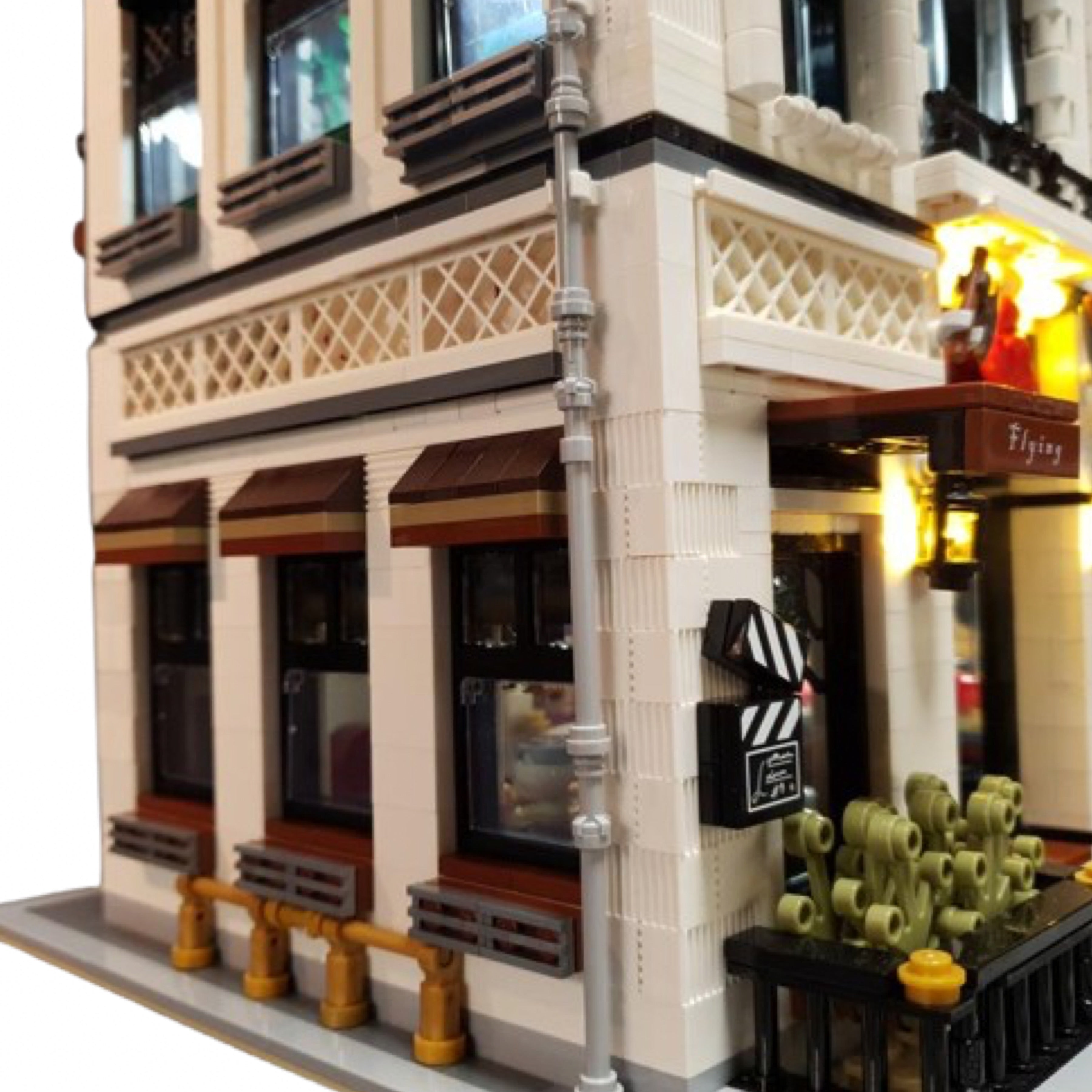 Corner exterior of seafood restaurant brick build with striped awning sign, potted greenery, and detailed latticework above the windows.