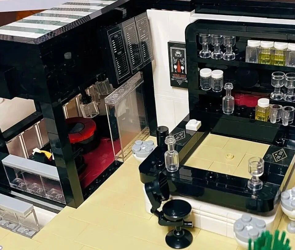Detailed bar area from the modular restaurant model with stools, drink shelves, wall décor, and a serving counter surrounded by black and white tiles.