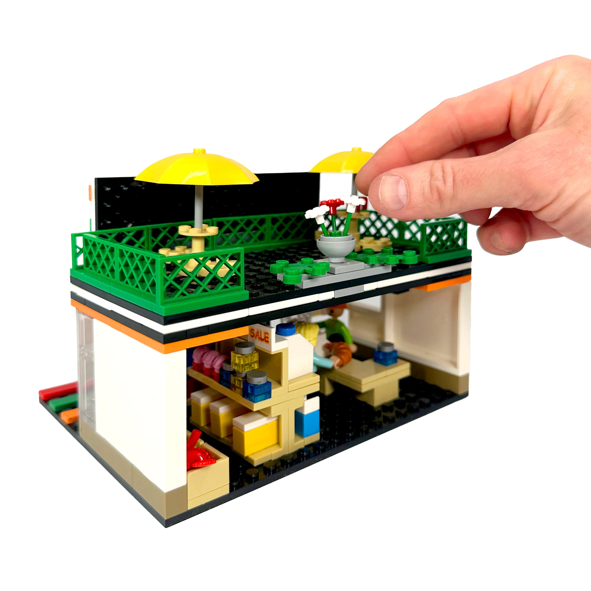 Back angled view of Gulp & Go city convenience store set with hand for size perspective